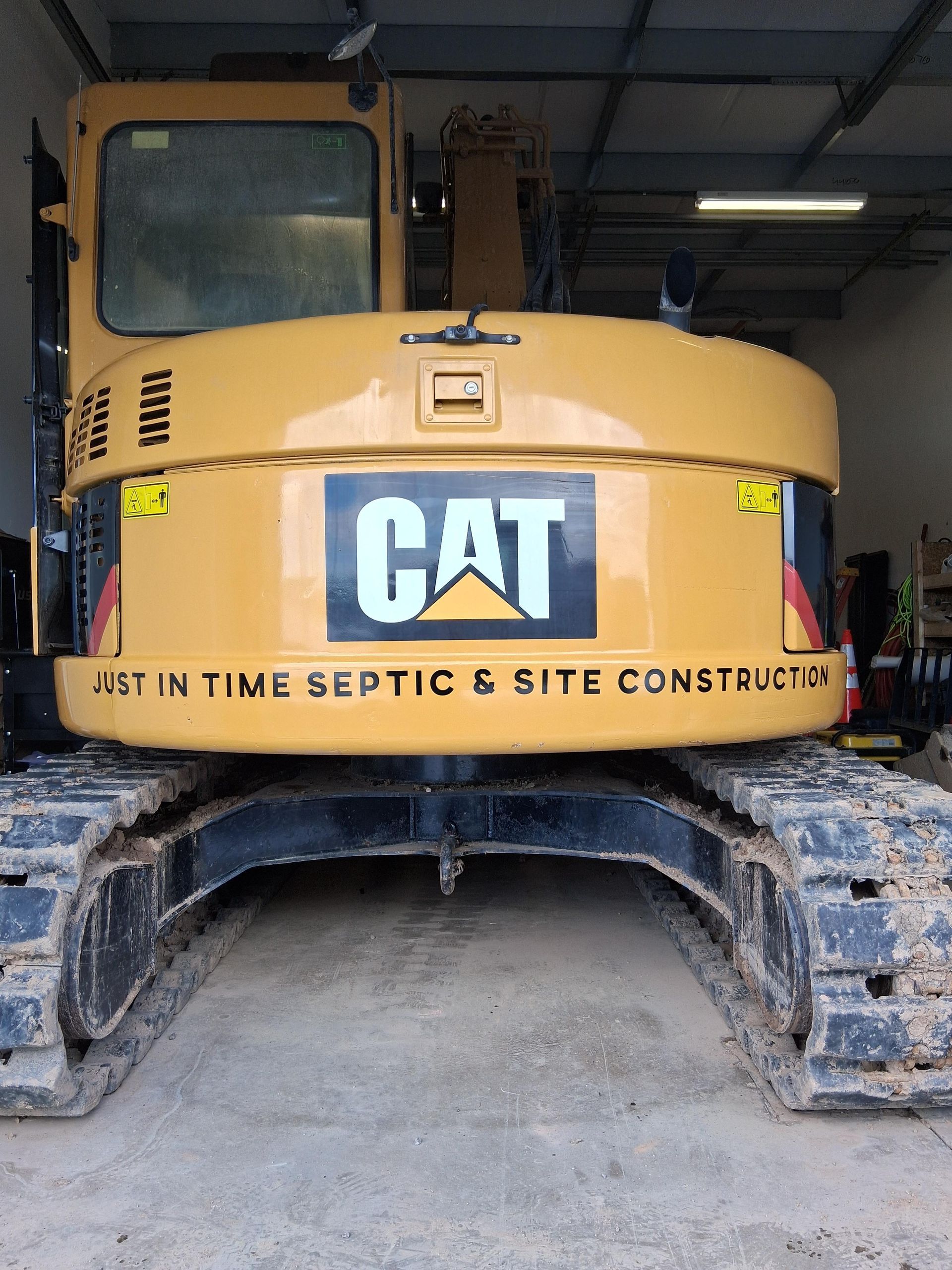 A yellow cat excavator is parked in a garage