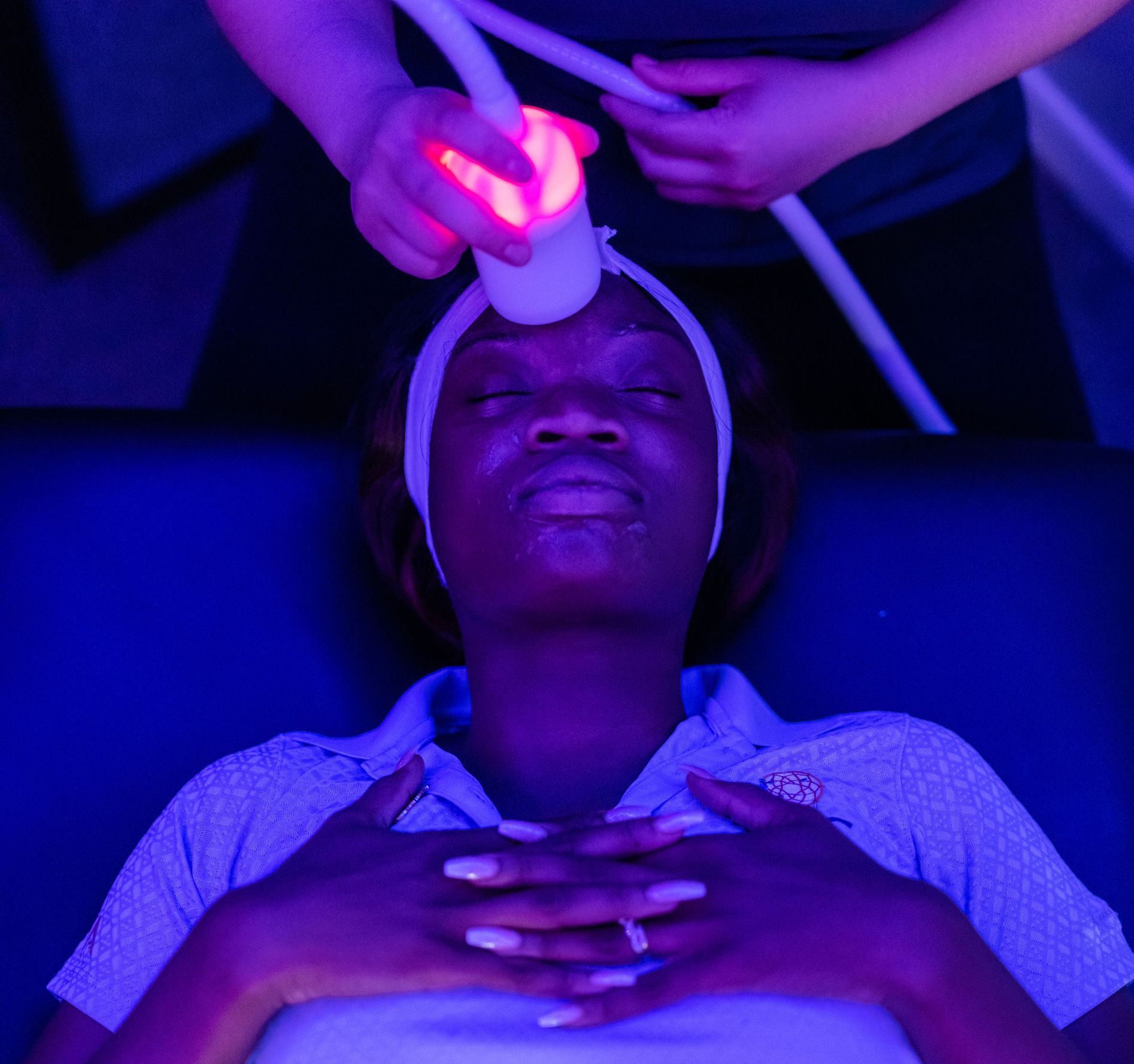 a woman is getting a treatment with a red light on her head
