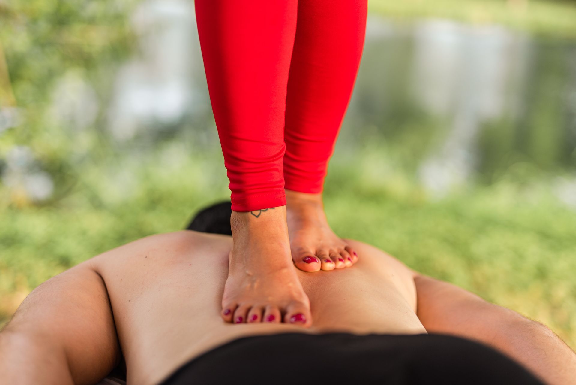 A woman is giving a man a massage with her feet on his back.