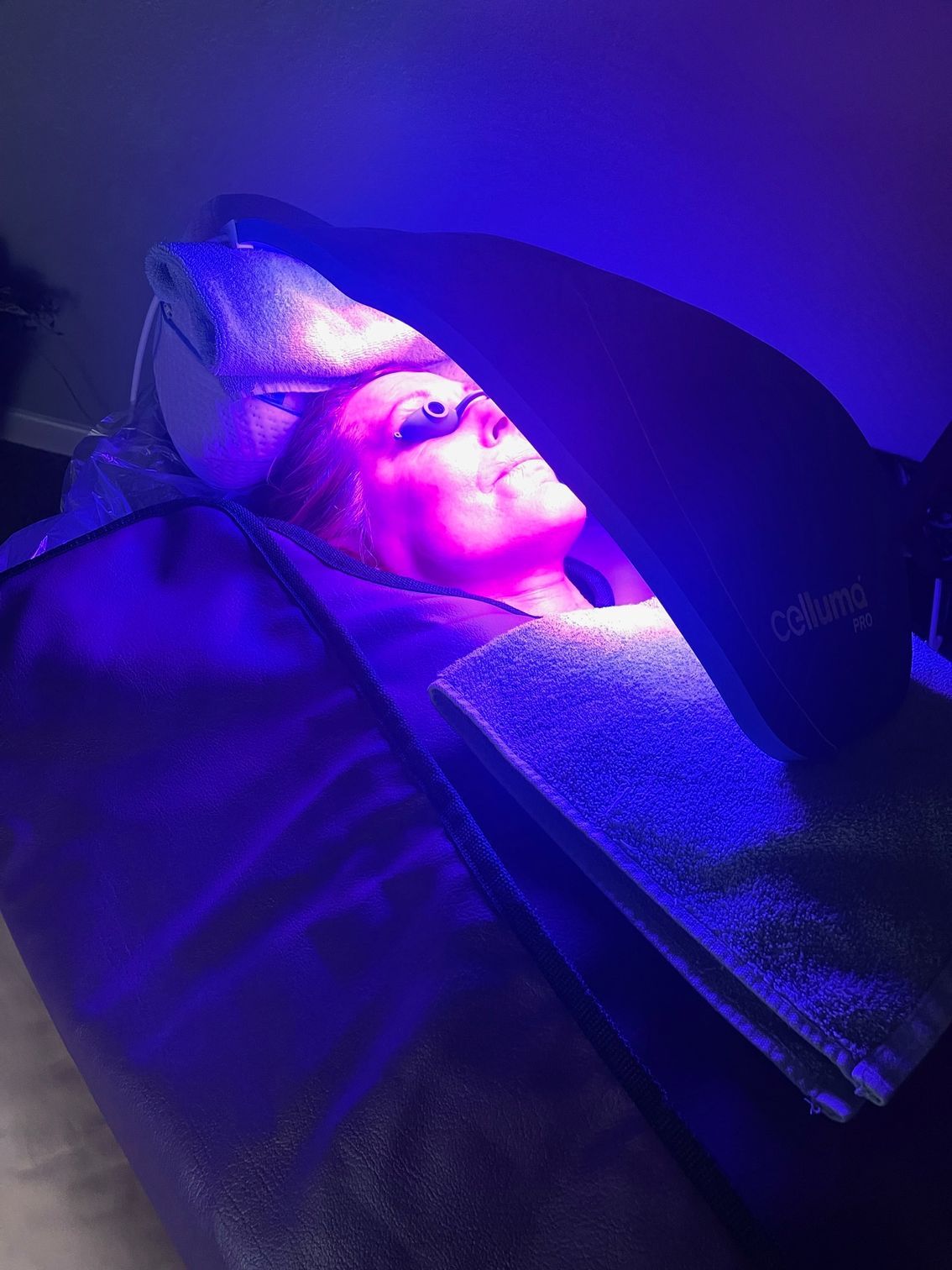 A woman is laying on a bed under a blue light.