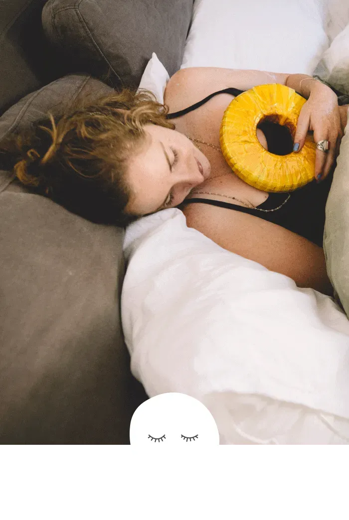 A woman is laying on a couch holding a pineapple