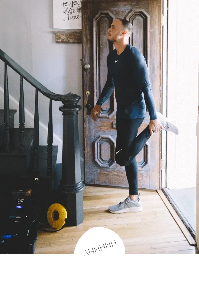 A man is stretching his leg in front of a door.