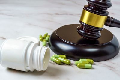 A judge 's gavel and a bottle of pills on a table.