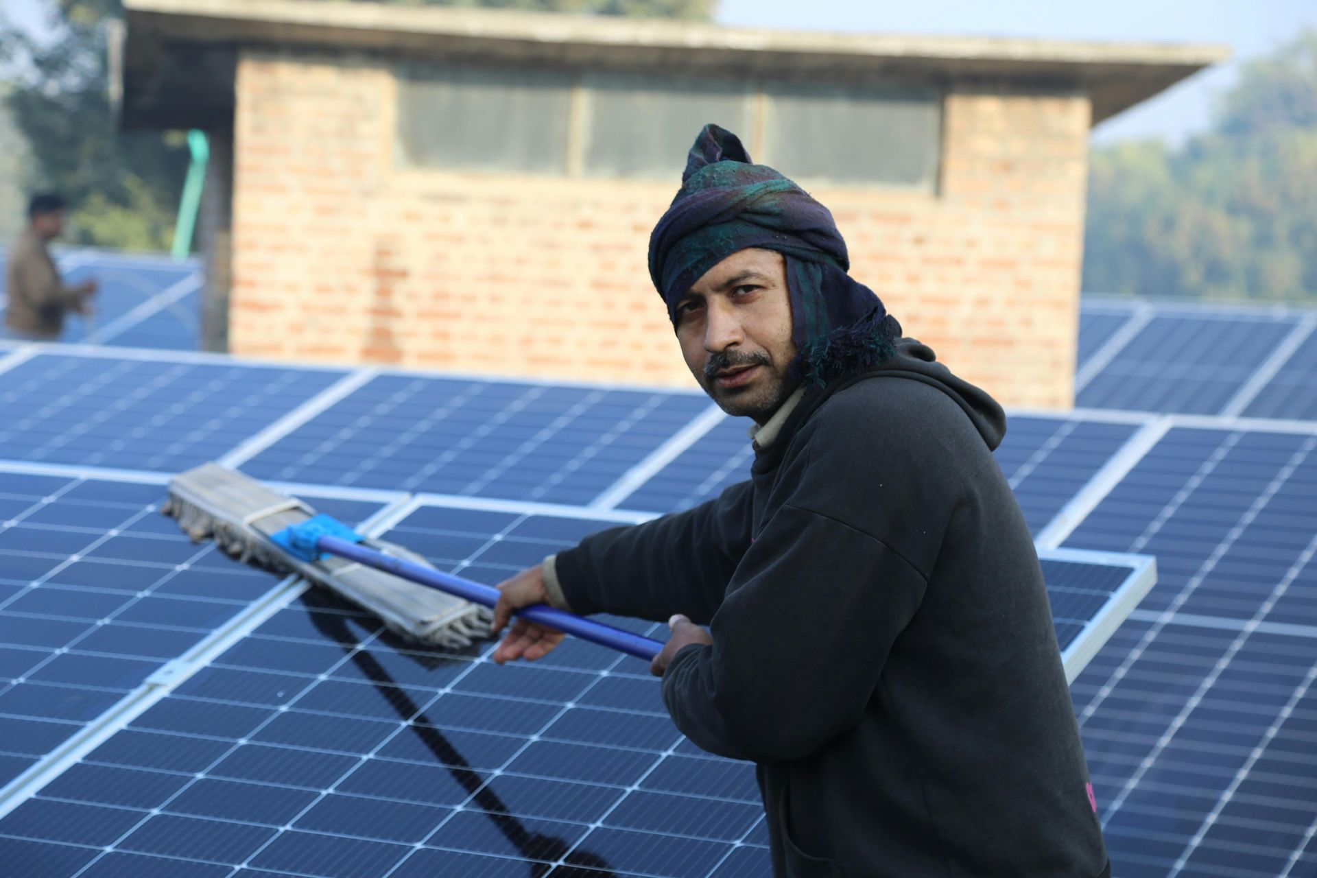 A man is cleaning a solar panel with a mop.