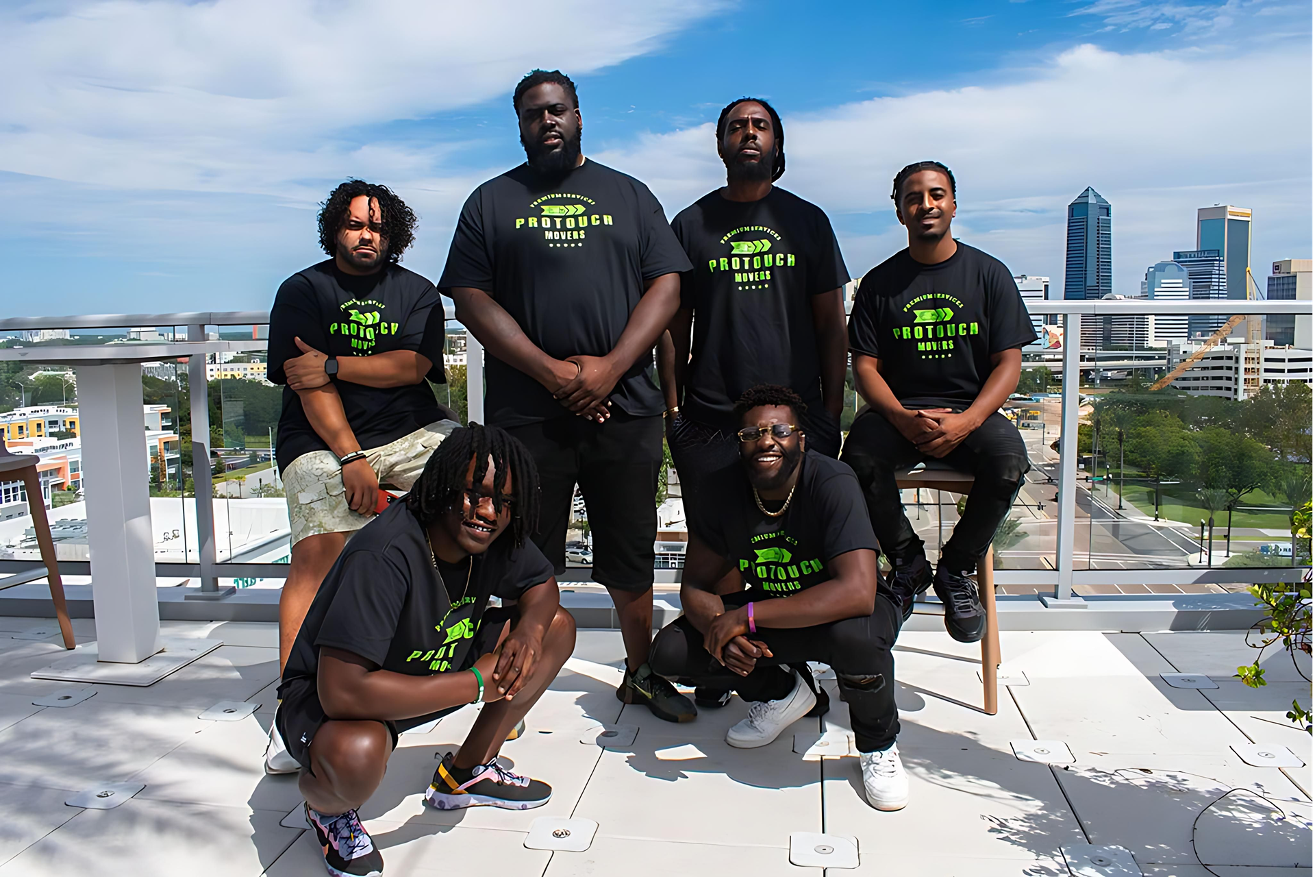 The Pro Touch Movers team posing on a rooftop overlooking downtown Jacksonville, Florida, wearing branded uniforms.