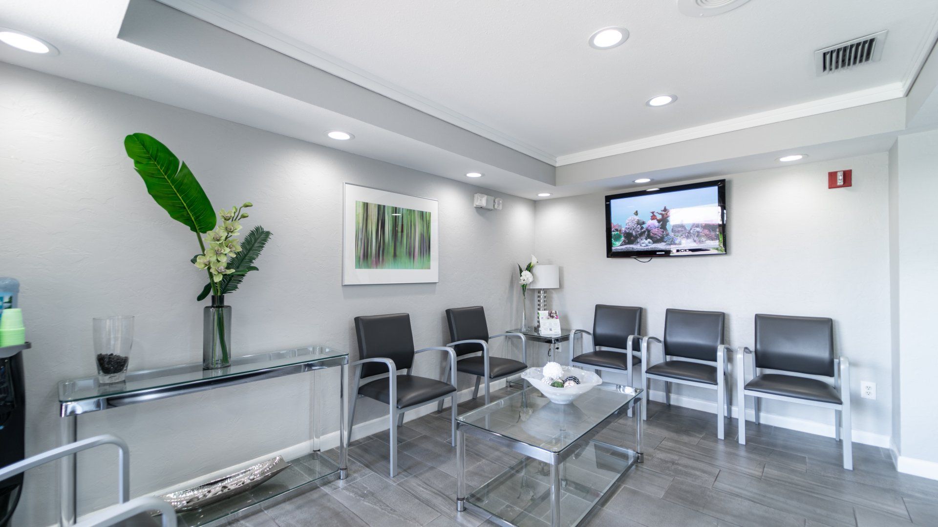 A waiting room with chairs , a table and a television.