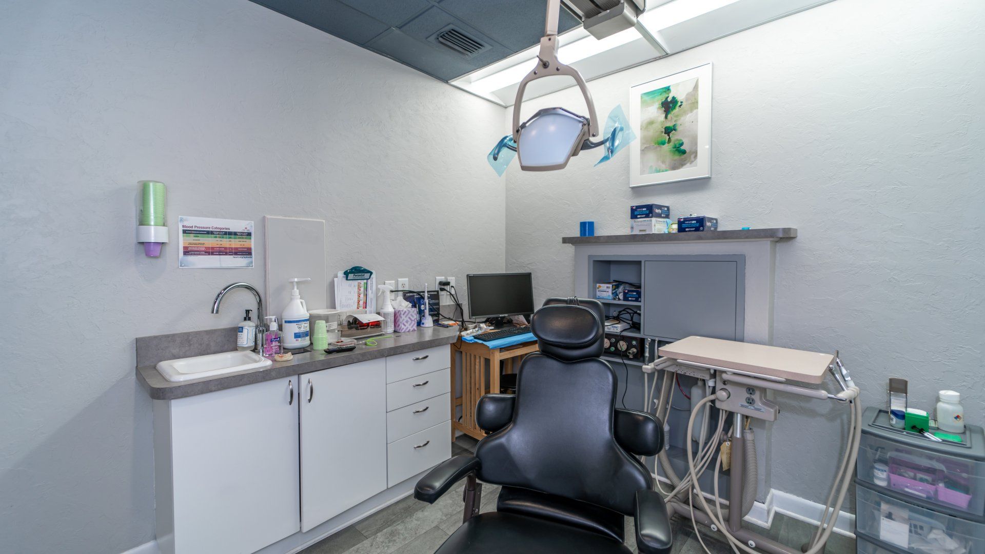 A dental office with a dental chair and a sink.