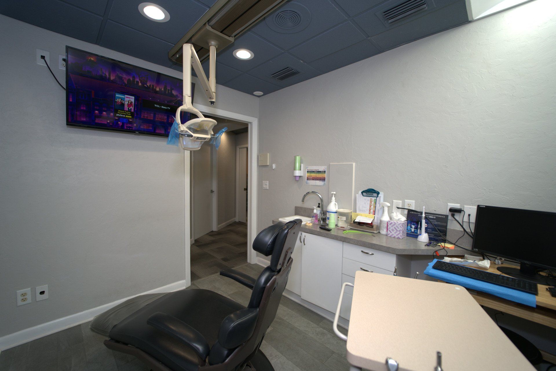 A dental office with a dental chair and a television on the wall.