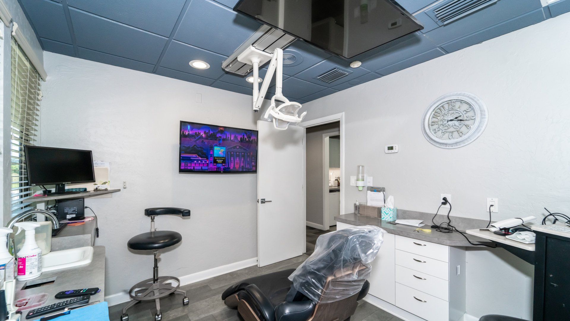 A dental office with a dental chair and a television on the wall.
