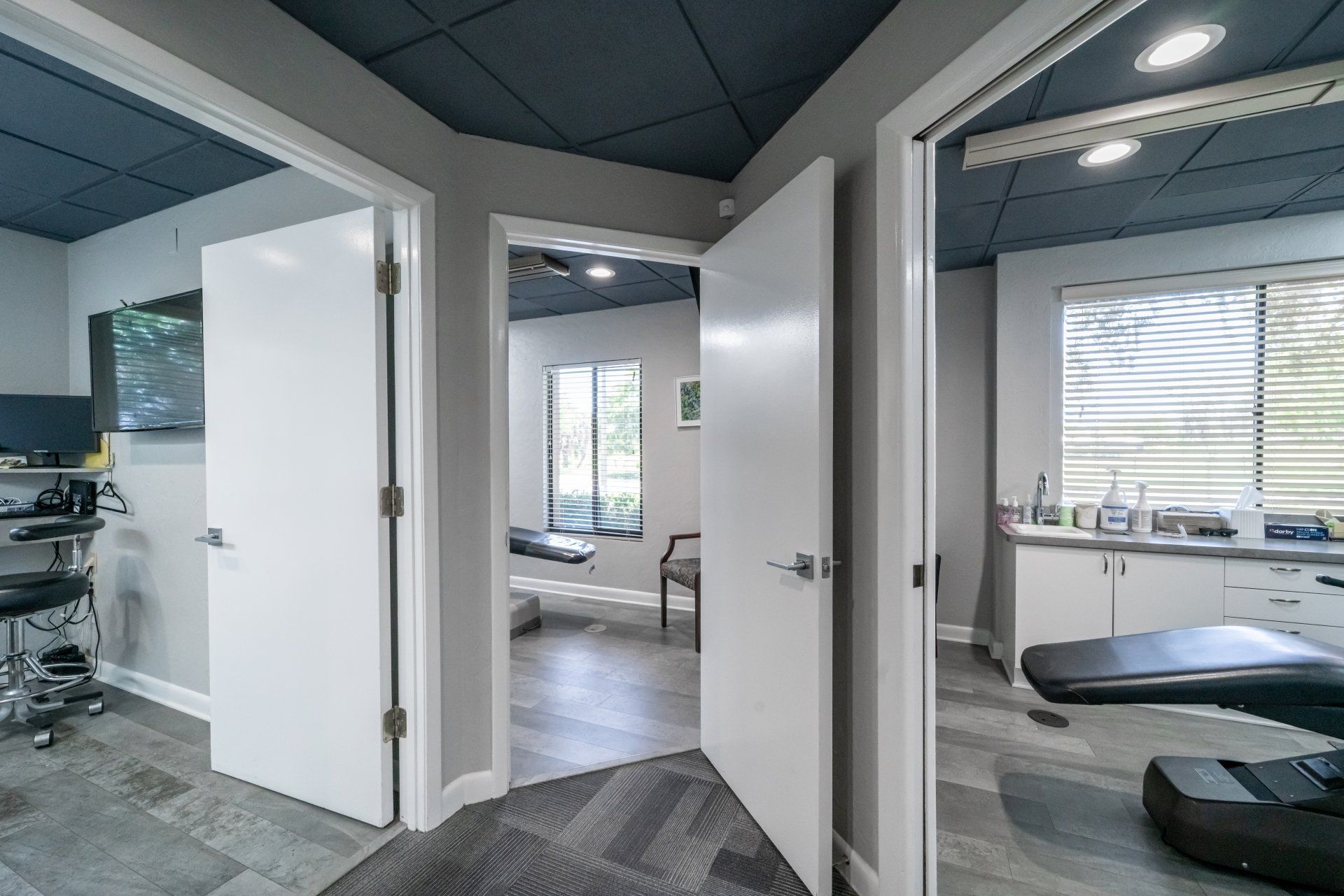 A dental office with two doors open and a dental chair in the middle of the room.