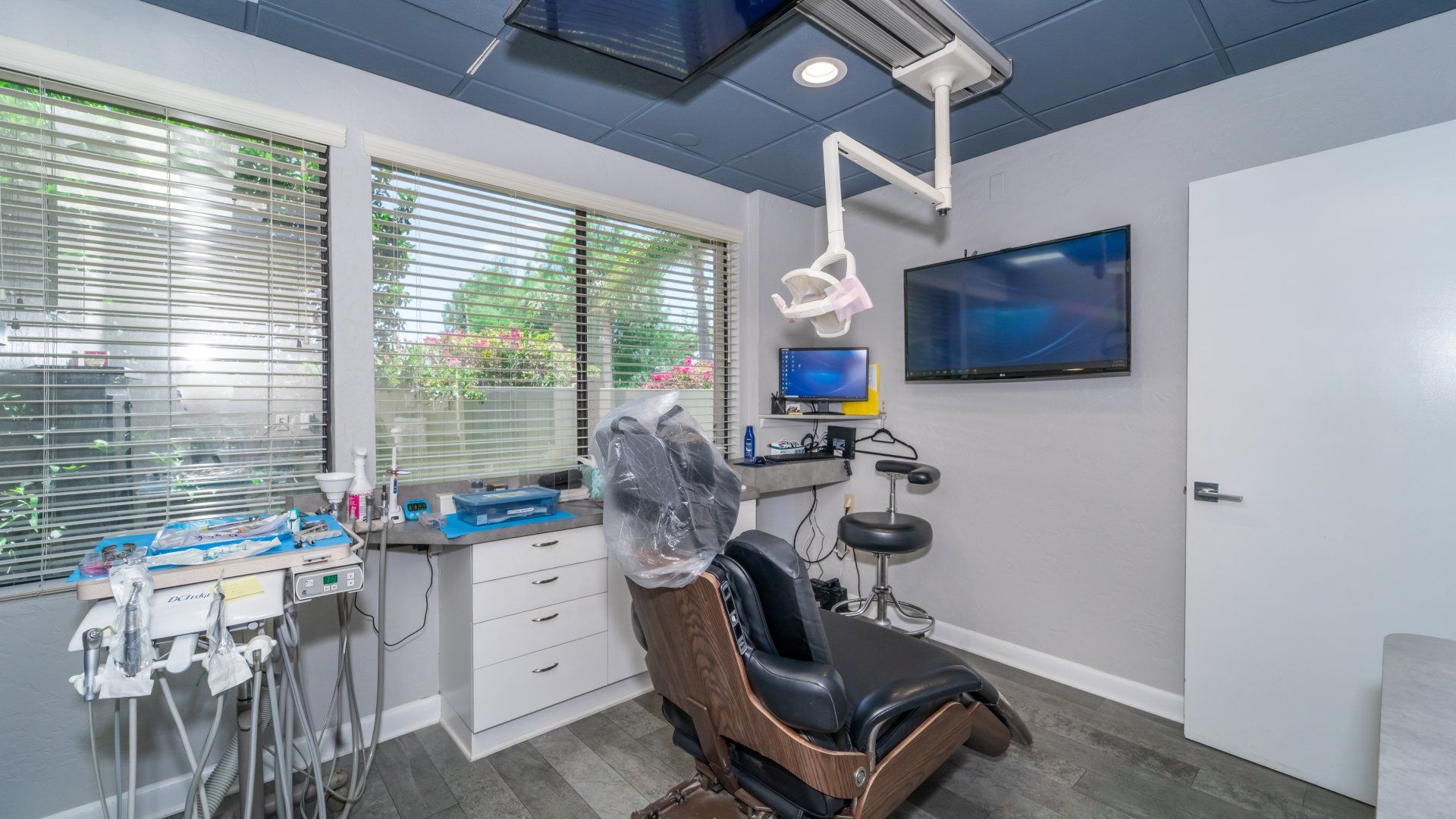A dental office with a dental chair and a television on the wall.