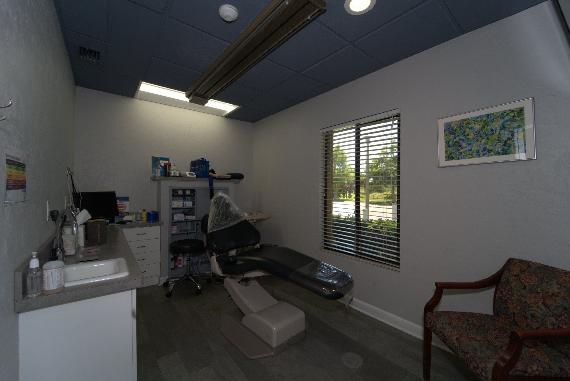 A dental office with a dental chair and a sink.