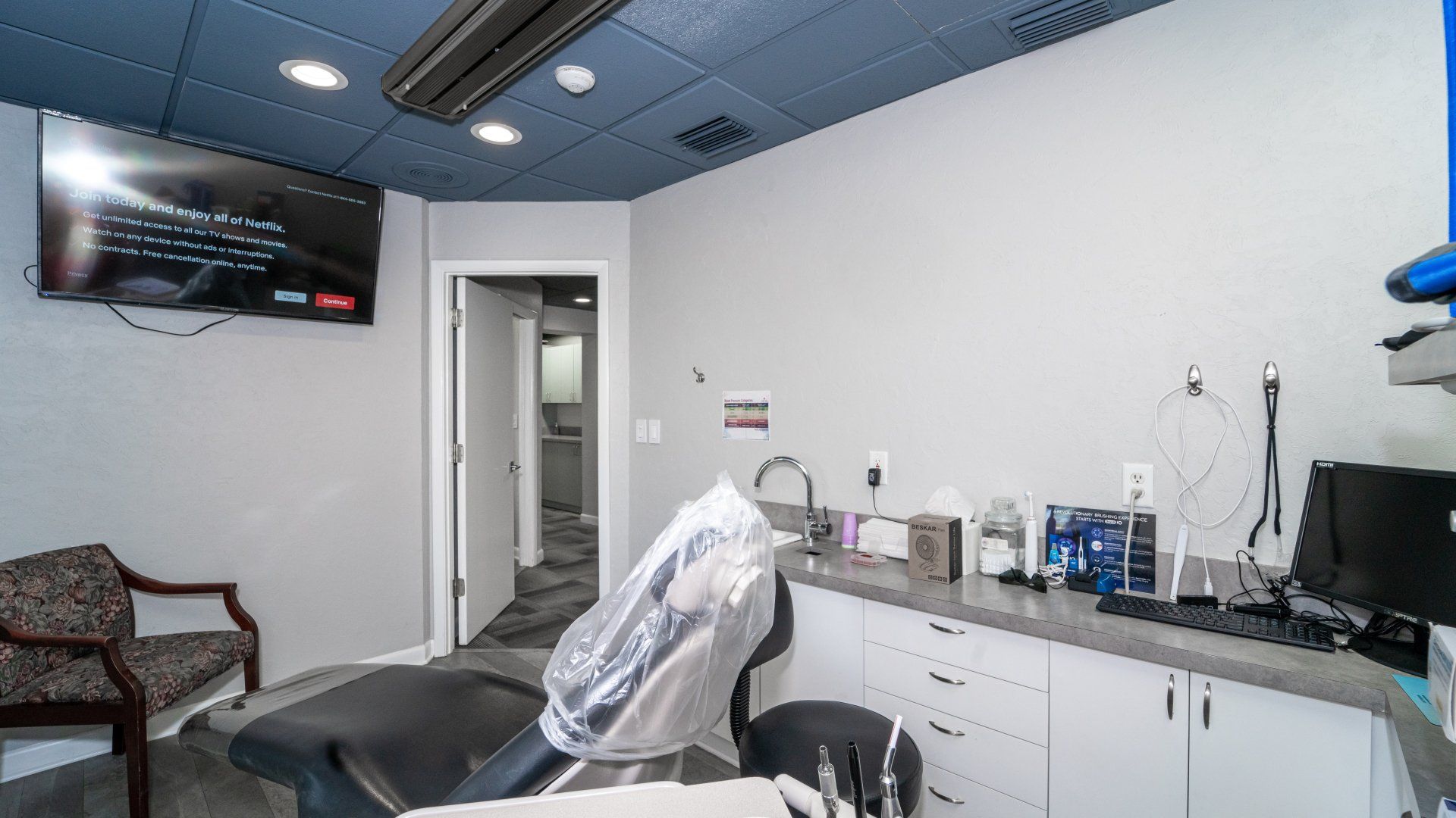 A dental office with a dental chair and a television on the wall.