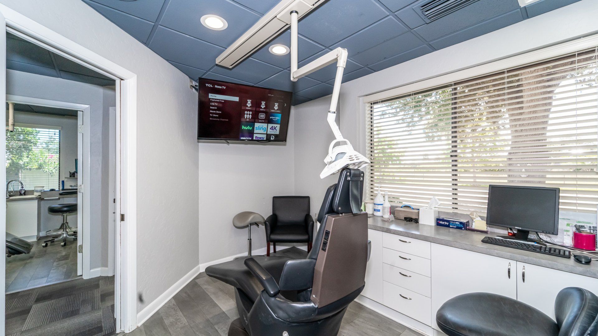 A dental office with a dental chair and a television on the wall.