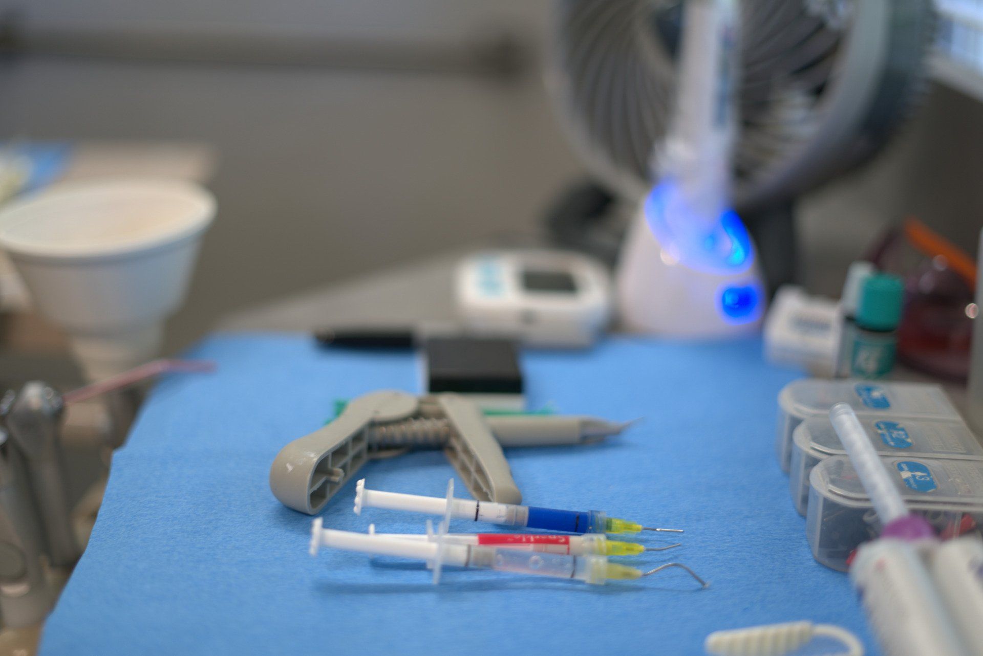 A table with a bunch of syringes on it and a fan in the background.