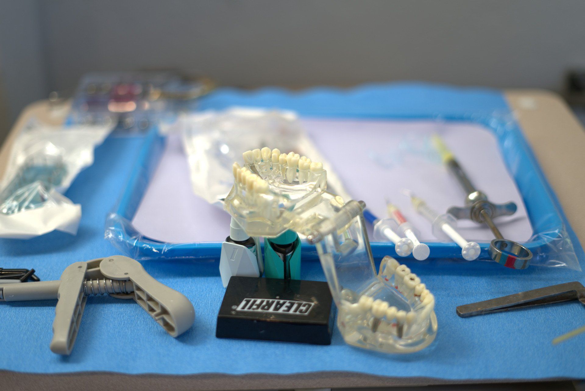 A tray of dental instruments and a model of teeth on a table.
