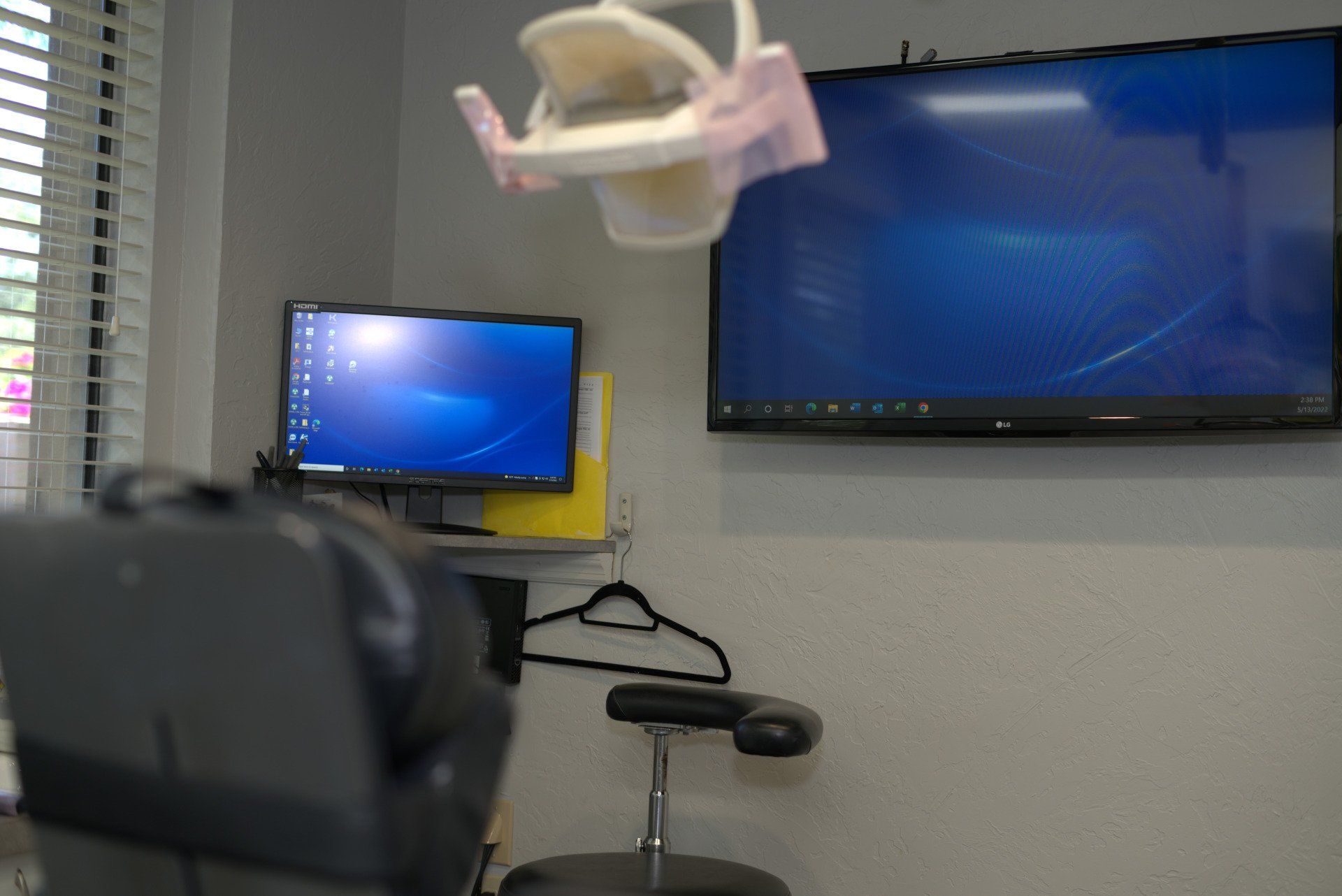 A dental office with a chair , computer , and television.