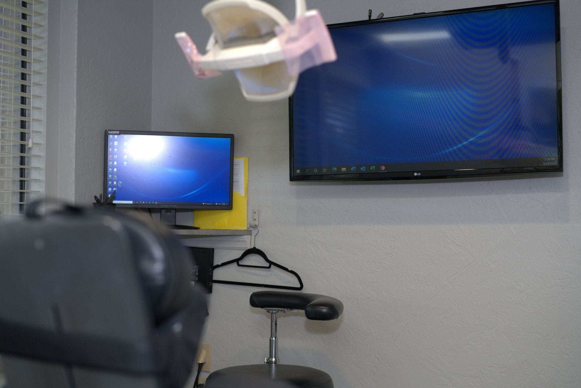 A dental office with a dental chair , monitor and television.