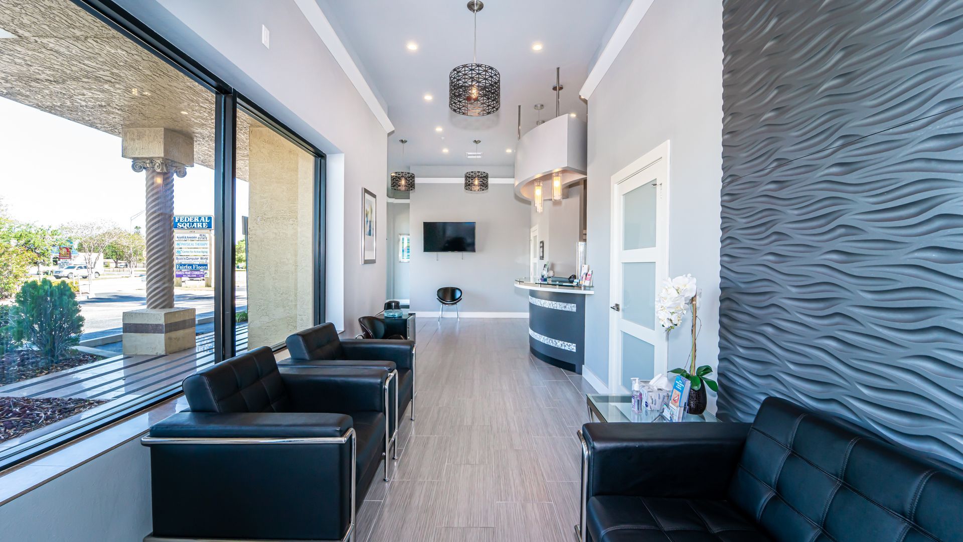 A waiting room with a couch and chairs in a dental office.