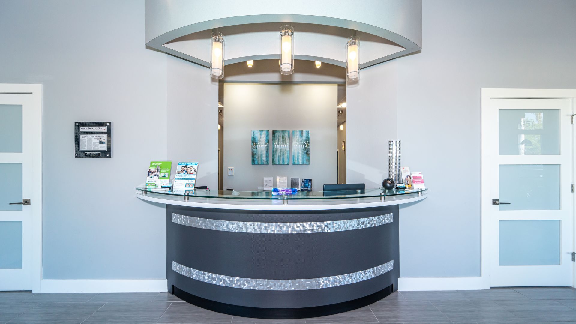 A reception desk in a dental office with a painting on the wall.