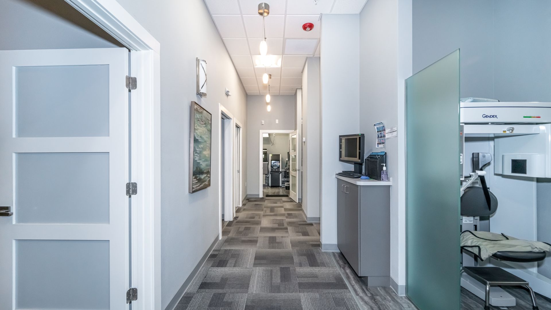 A long hallway in a dental office with a computer on the wall.