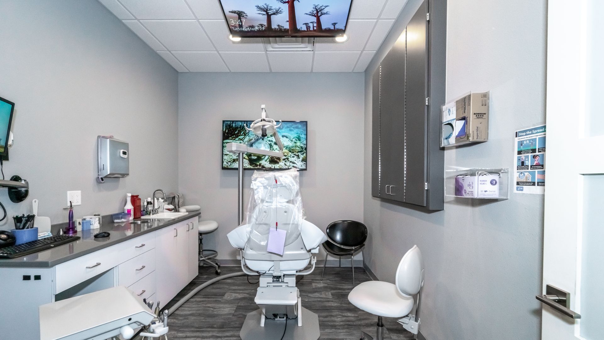 A dental office with a dental chair and a television on the wall.