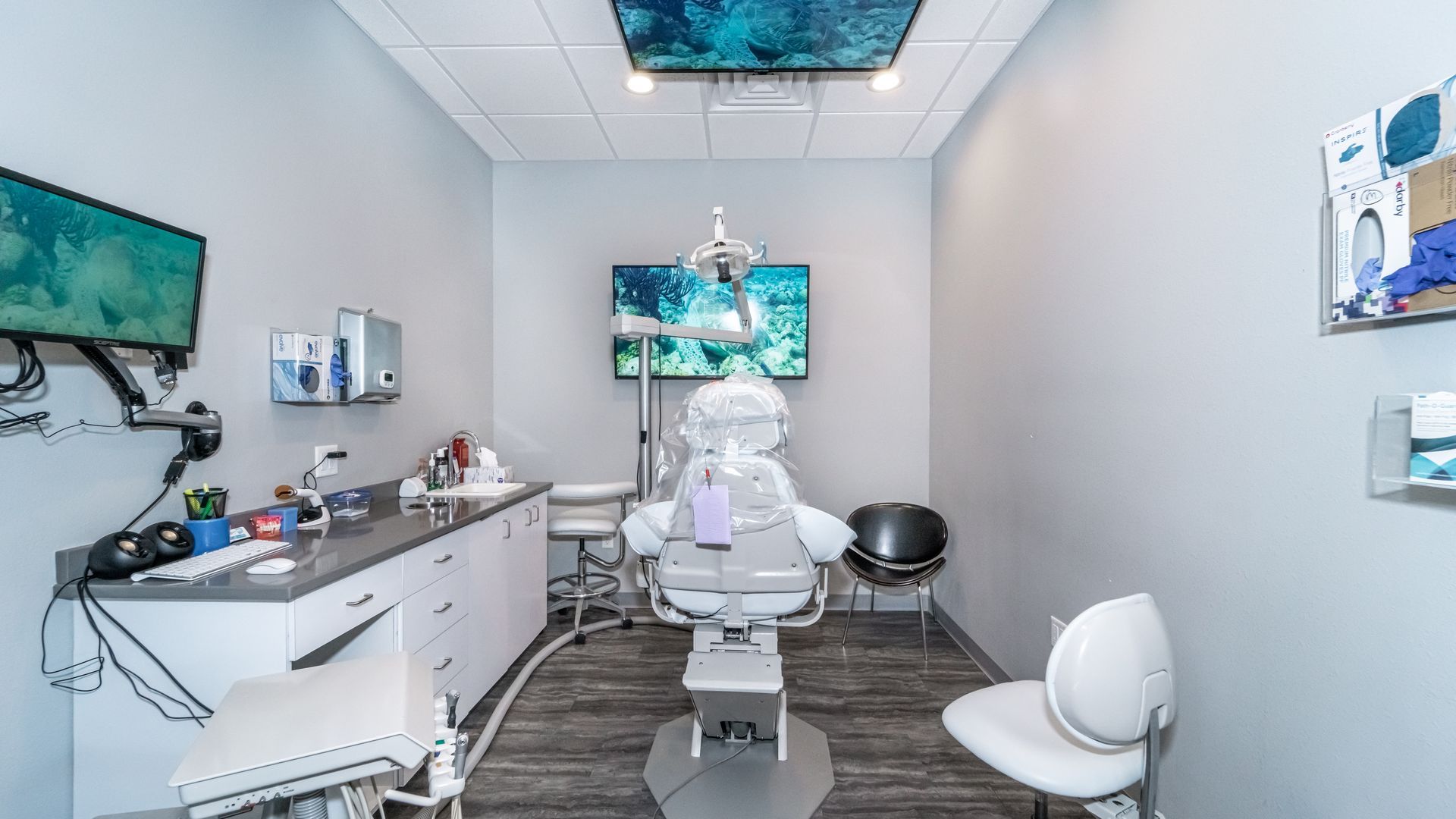 A dental office with a dental chair and a television on the wall.