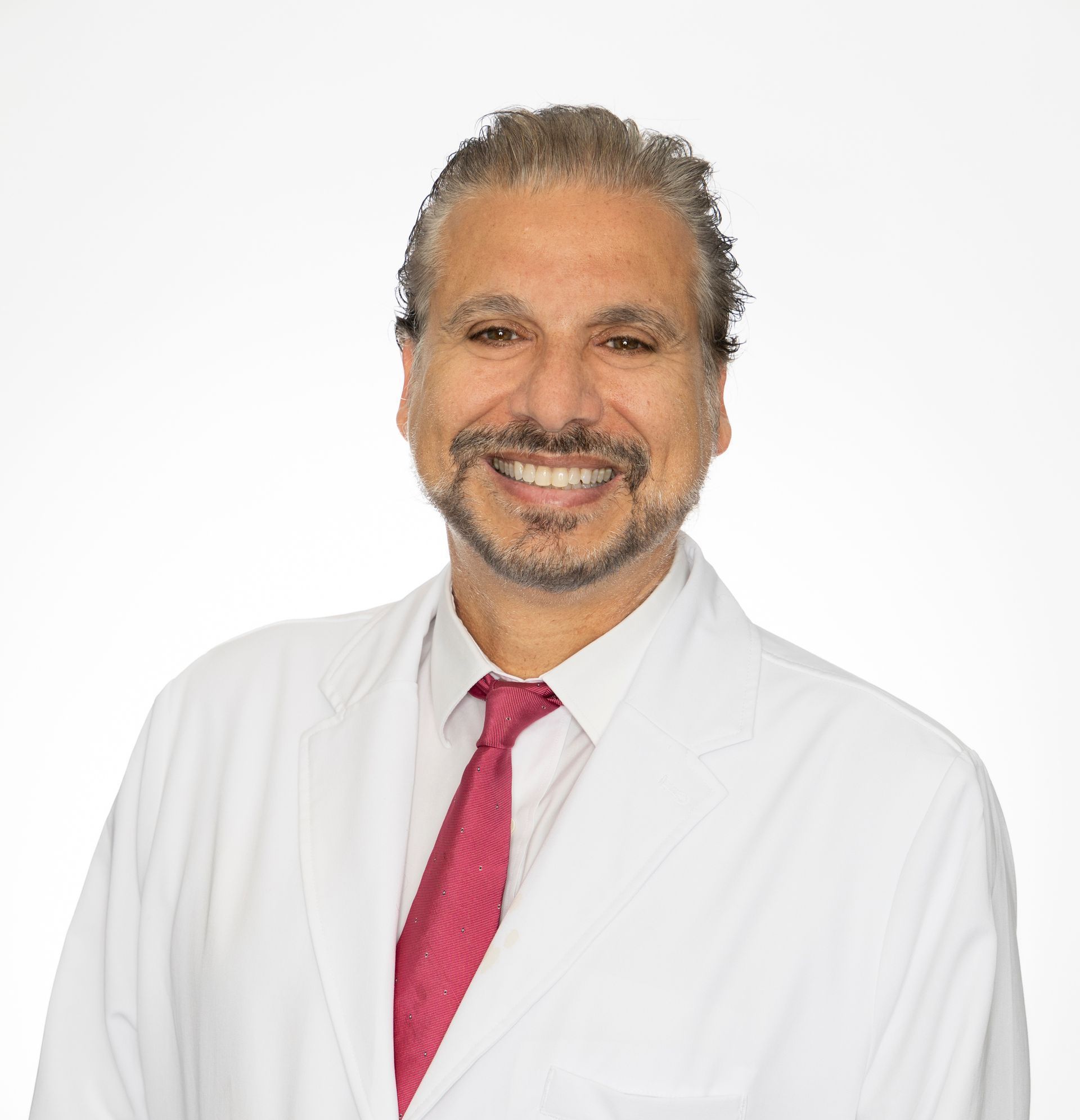 A man in a blue suit and white shirt is smiling with his arms crossed.