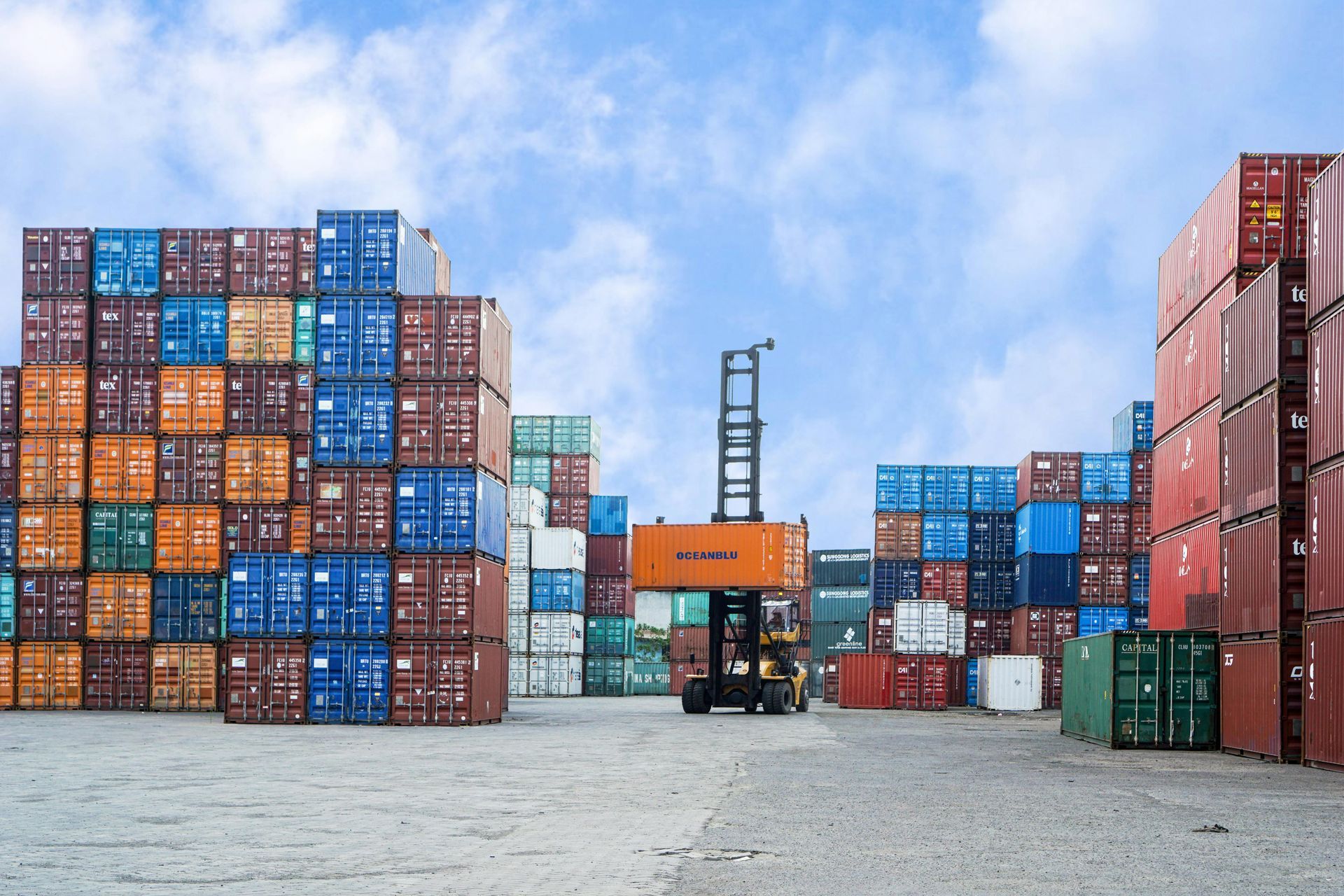 A forklift is moving a stack of shipping containers in a warehouse.