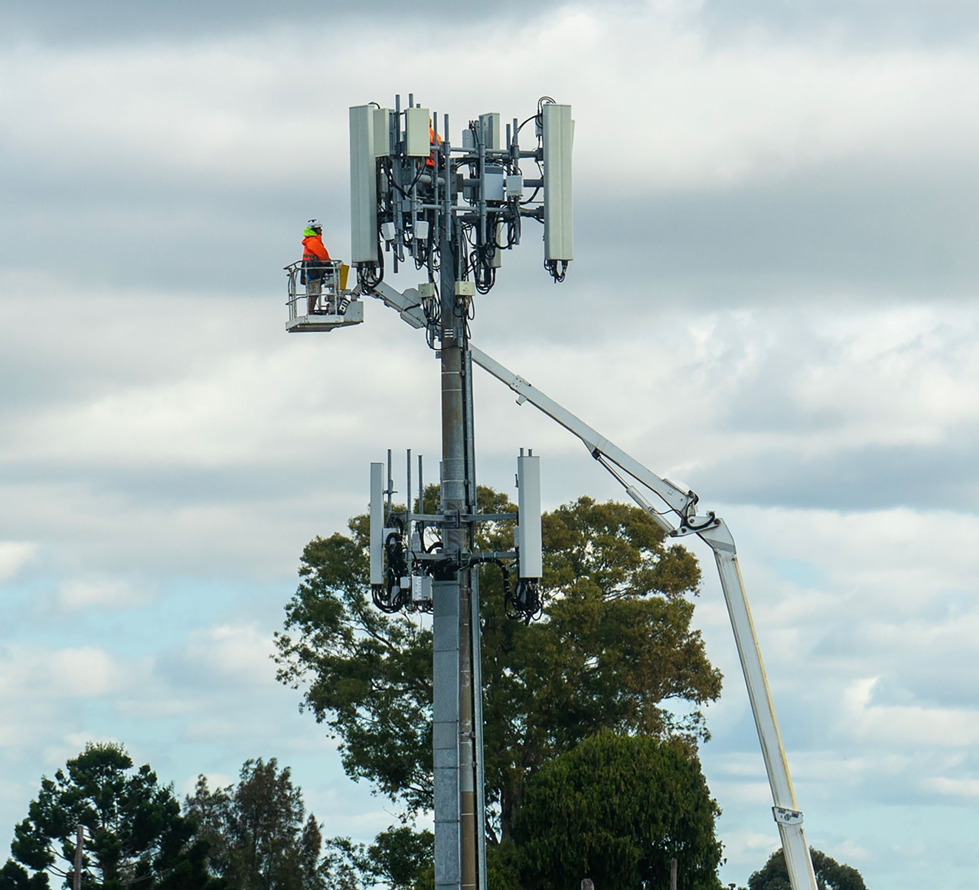 A man in a bucket is working on a cell phone tower