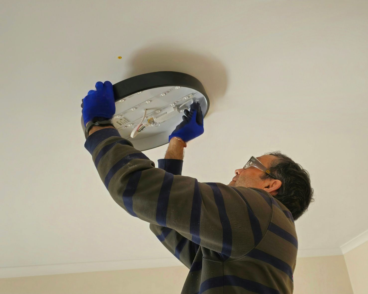 A man is fixing a light fixture on the ceiling