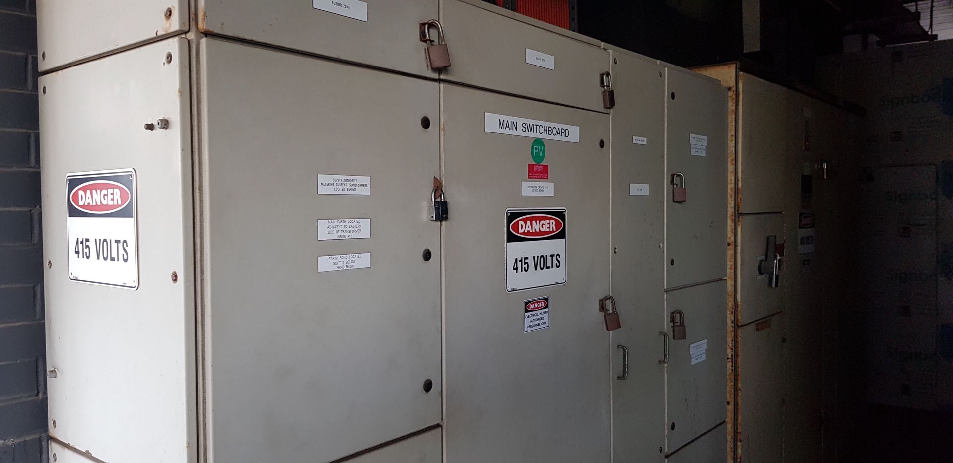 A row of electrical cabinets with warning signs on them.