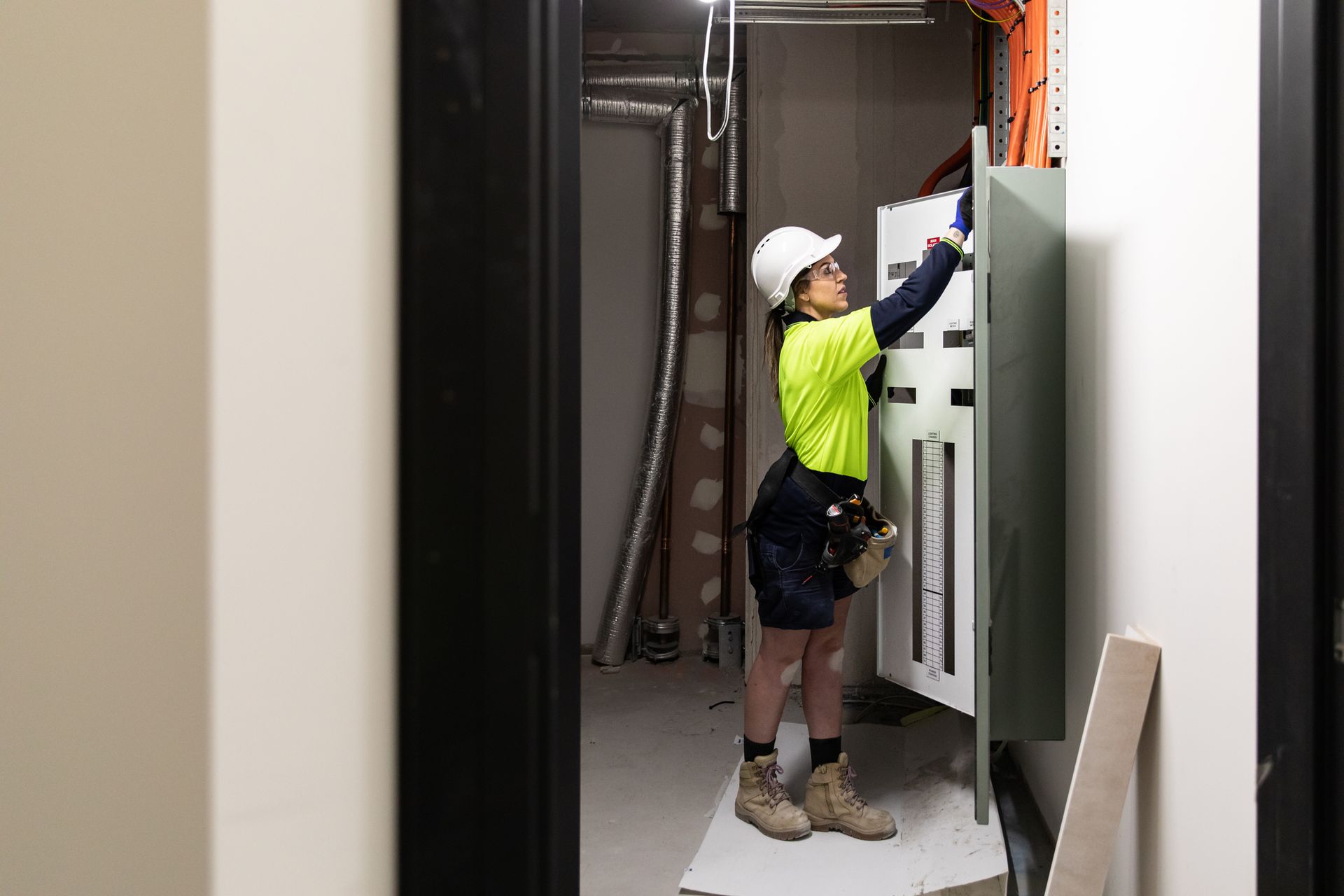 A woman is working on an electrical box in a room.