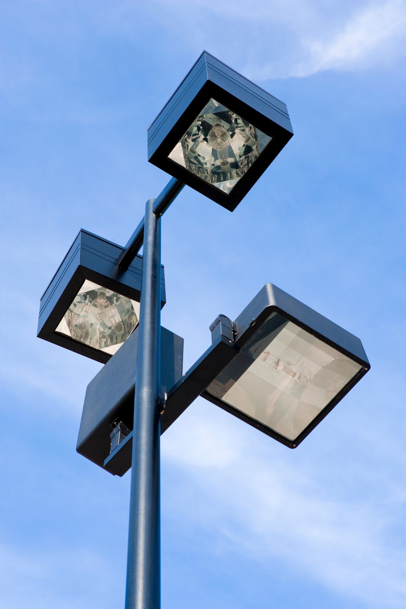 A street light with three square lights on it against a blue sky