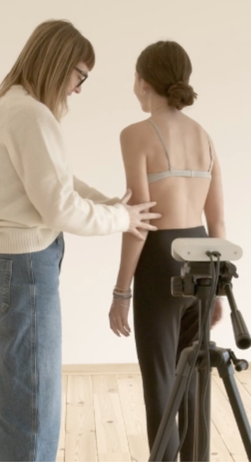 A woman is measuring a woman 's arm in front of a tripod.