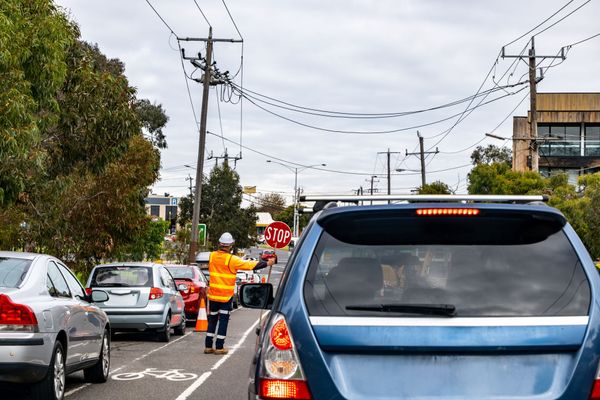 Traffic jam on a city street with a road worker in orange directing cars near a blue SUV