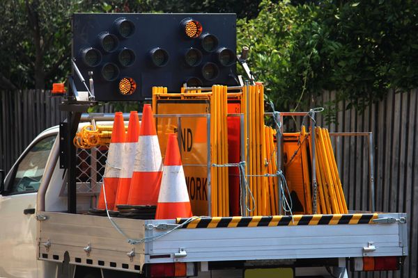 Truck bed loaded with orange traffic cones and road barriers at a worksite