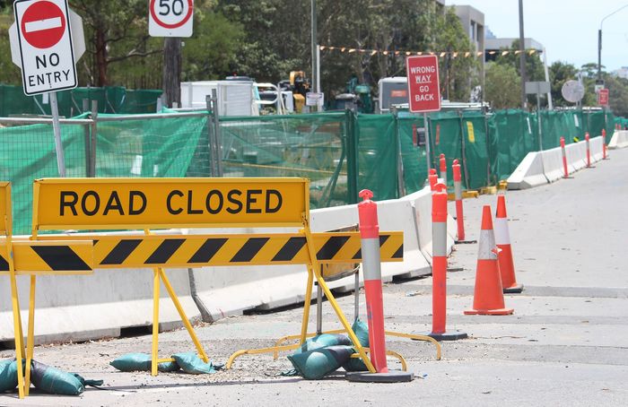 Road closed sign and orange traffic cones blocking a street construction area