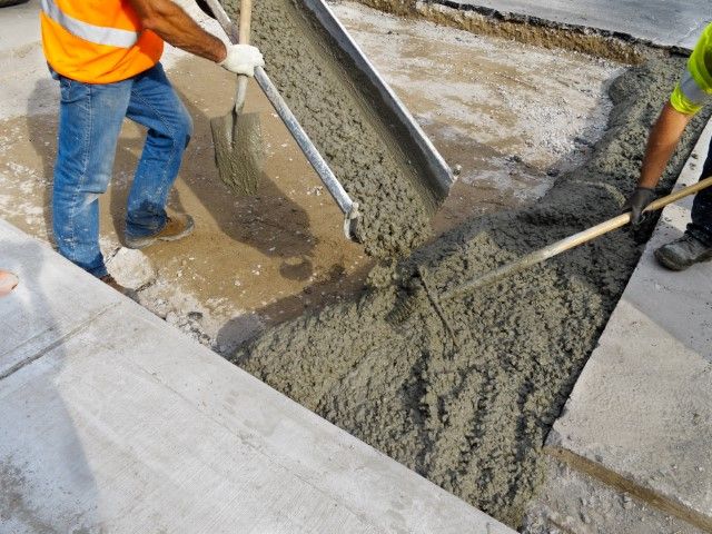 pouring concrete into a surface and spreading them around.
