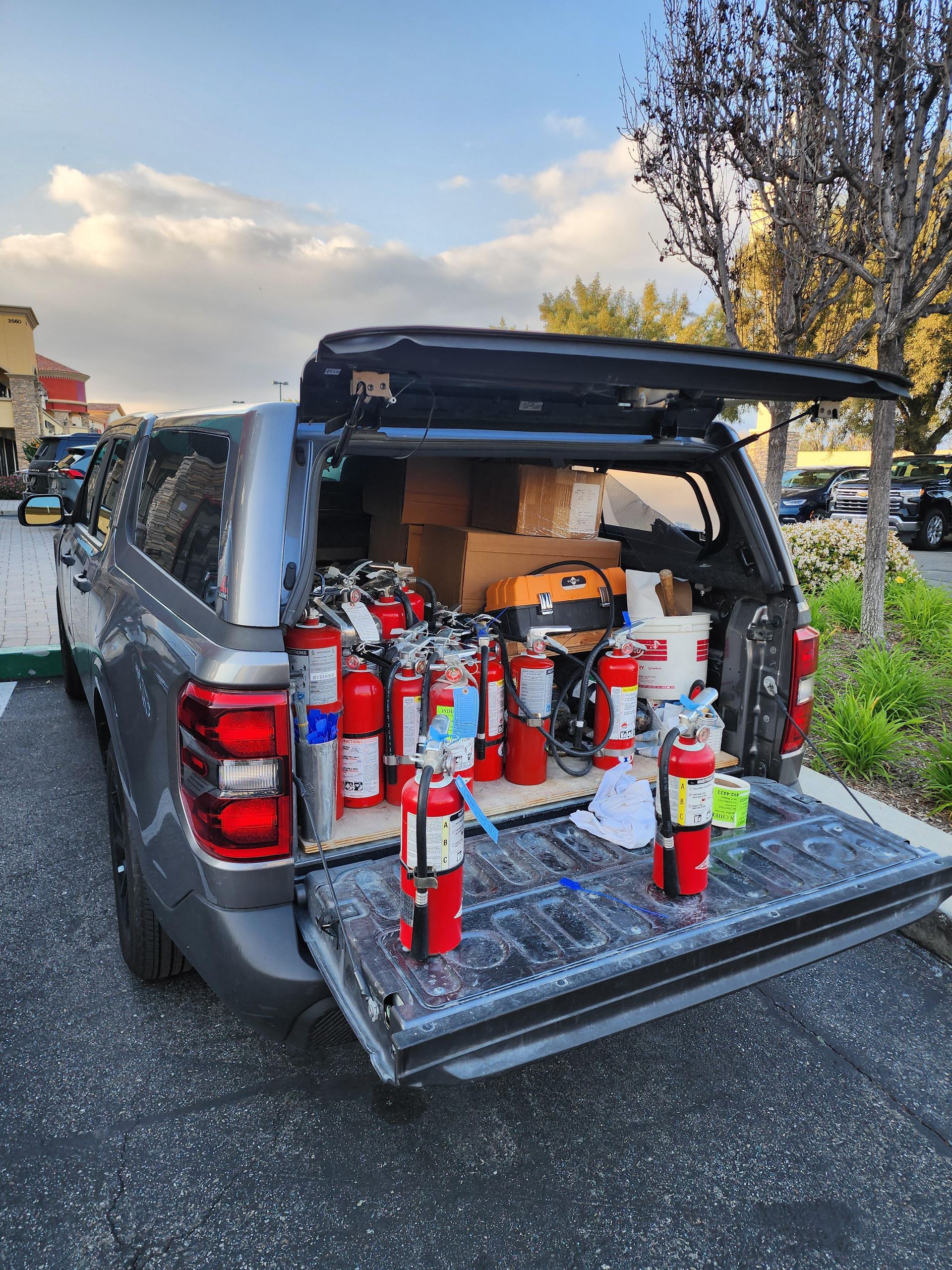The back of a truck is filled with fire extinguishers.