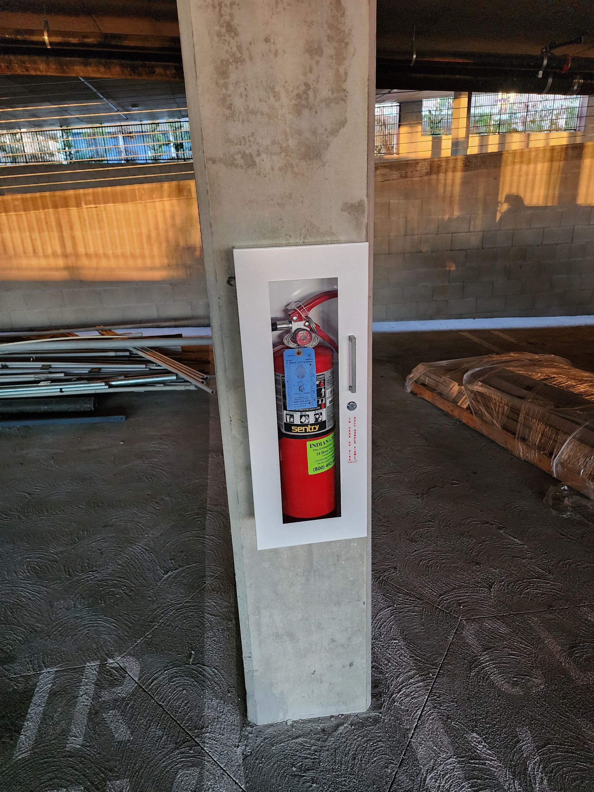 A fire extinguisher is mounted on a concrete pole in a garage.