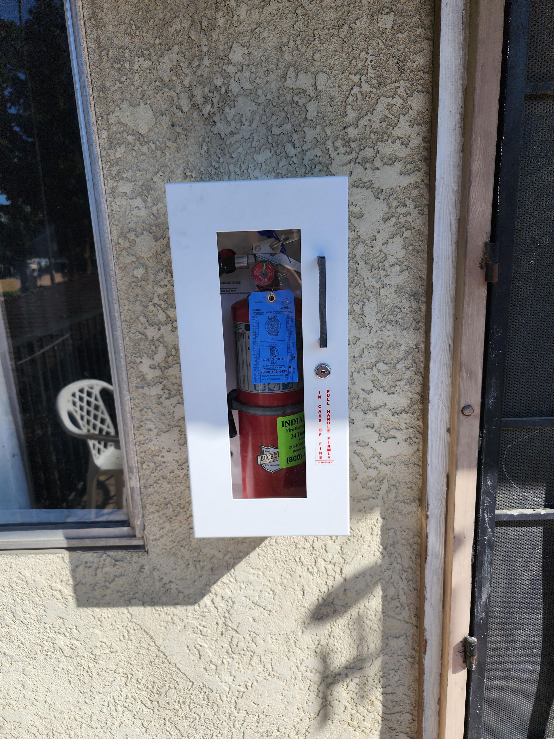 A fire extinguisher is in a white box on the side of a building