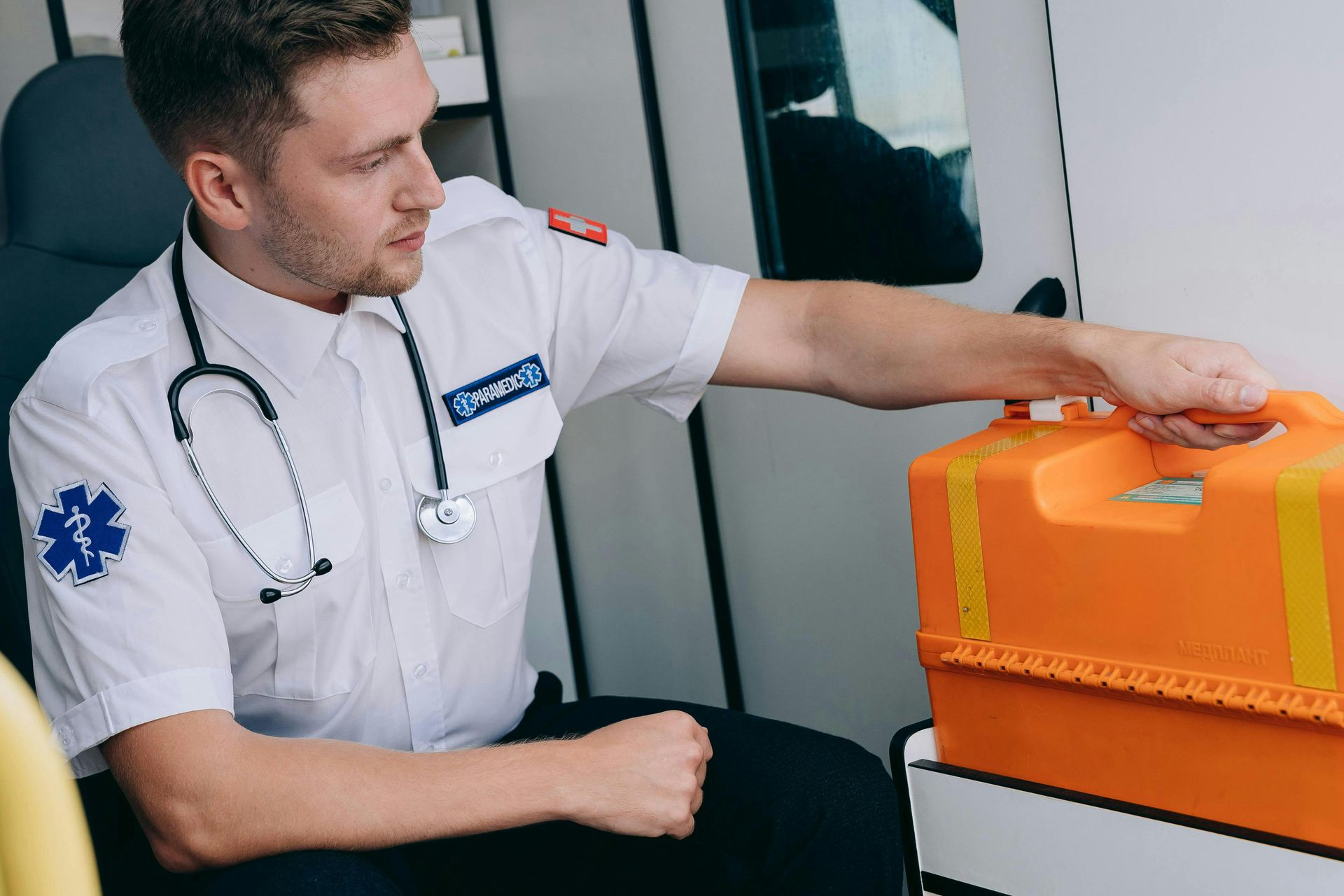 A paramedic is sitting in an ambulance looking at a box.