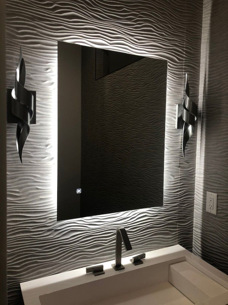 A bathroom with a sink and a mirror with lights on it.