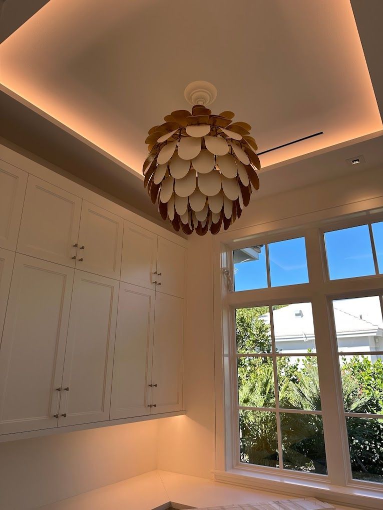 A chandelier is hanging from the ceiling of a room with a large window.