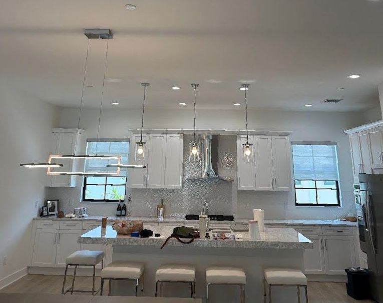 A kitchen with white cabinets and stools and a large island.