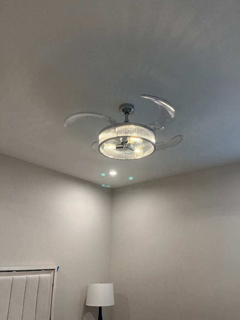 A bedroom with a ceiling fan and a lamp.