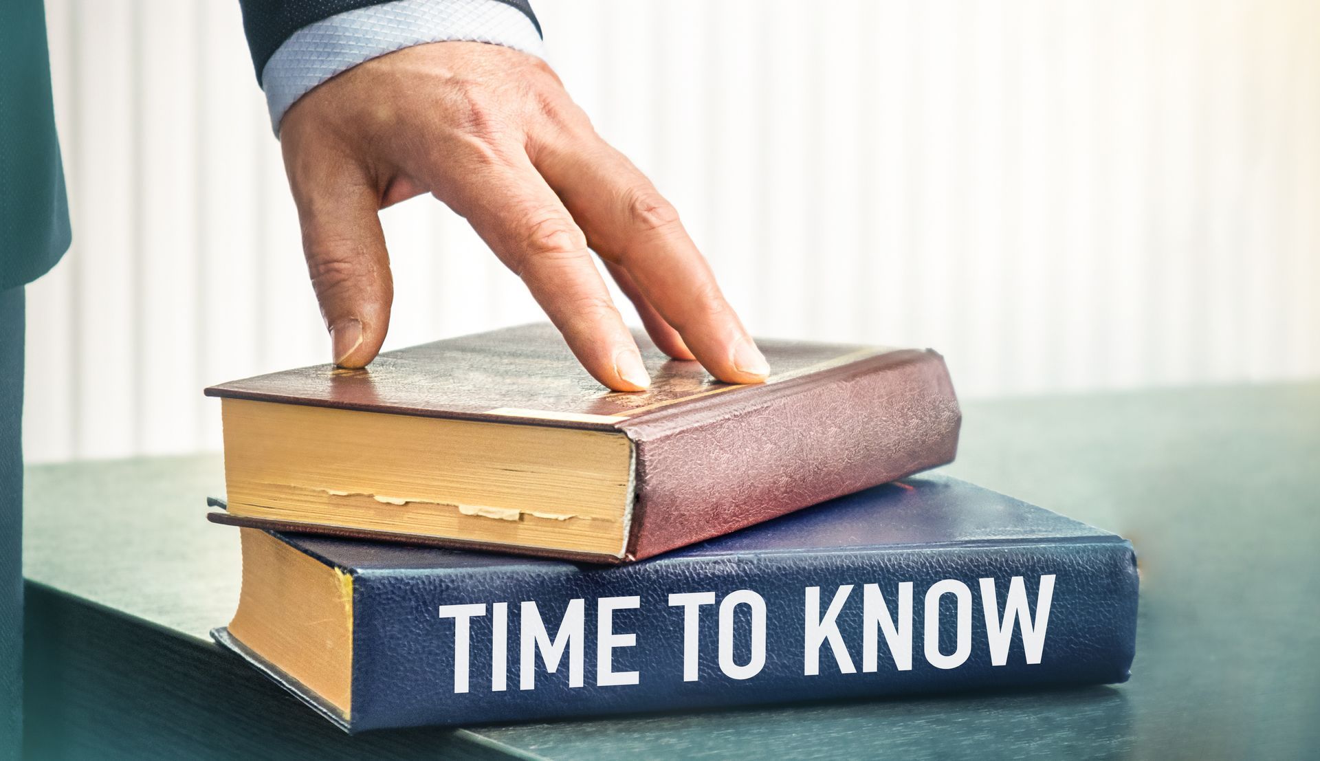 A person is touching a book that says `` time to know ''.