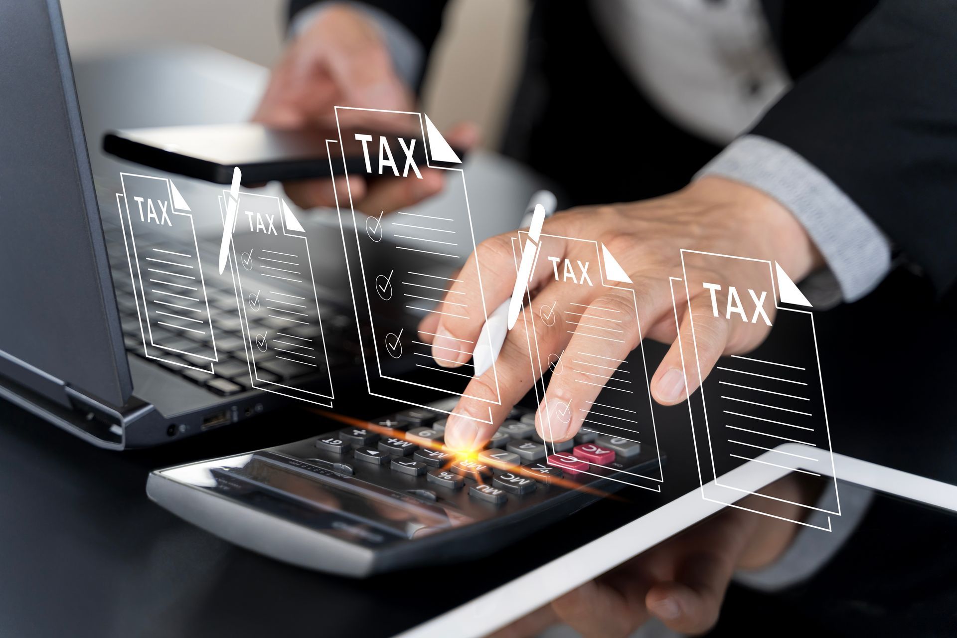 A man is using a calculator to calculate taxes while holding a cell phone.