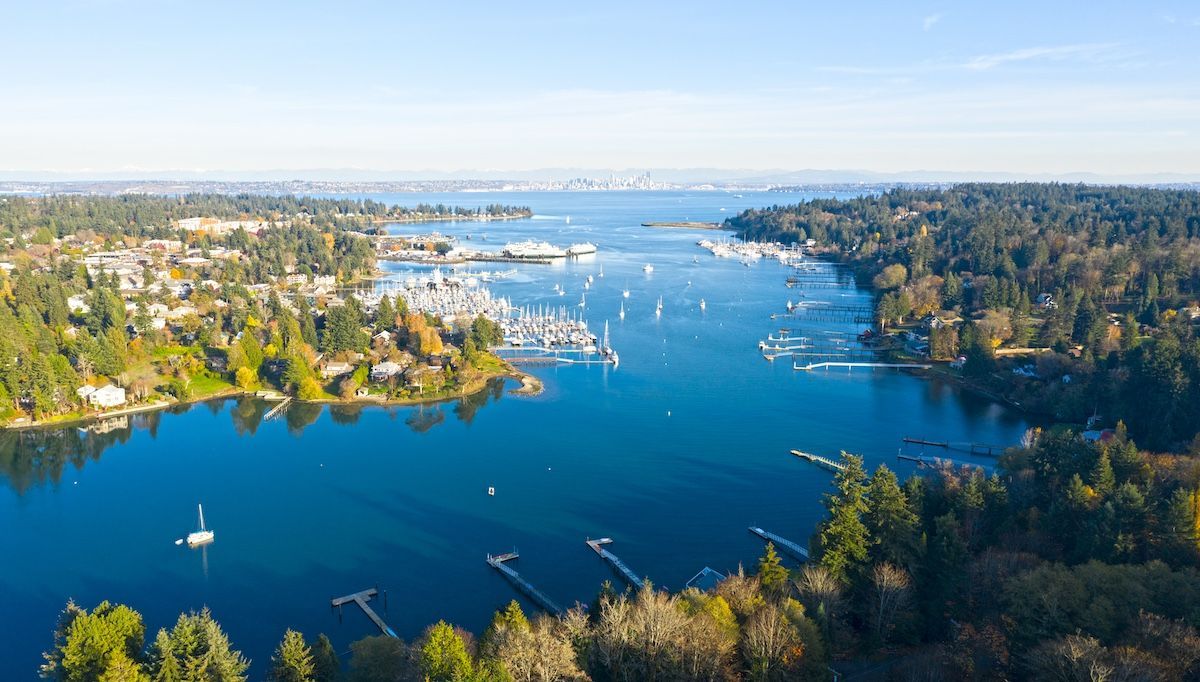 Aerial view of a dirt path separating two bodies of water next to a small village on a sunny day.